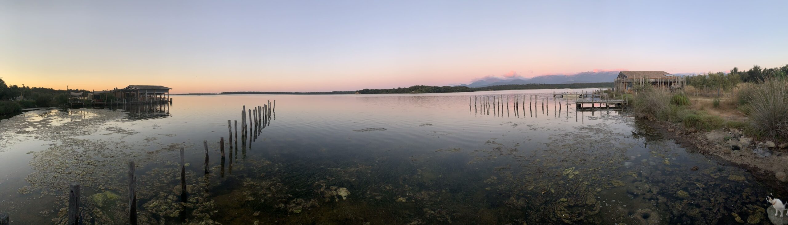 Lever de soleil sur un lac calme avec des maisons sur pilotis