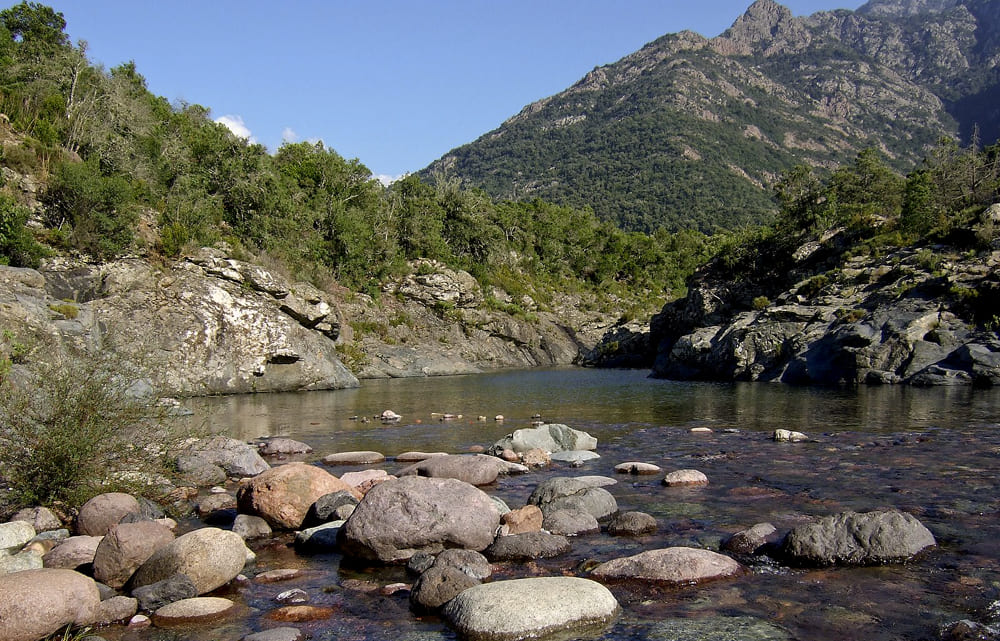 Paysage de montagne en Corse avec une rivière et des rochers