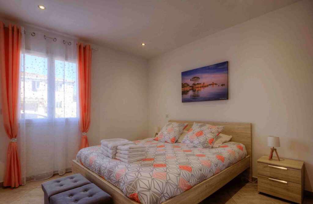 Chambre avec lit double, rideaux orange, et grande fenêtre