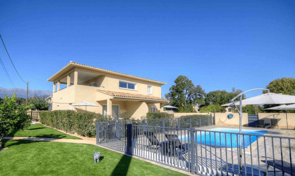 Maison à deux étages avec piscine clôturée et jardin bien entretenu.