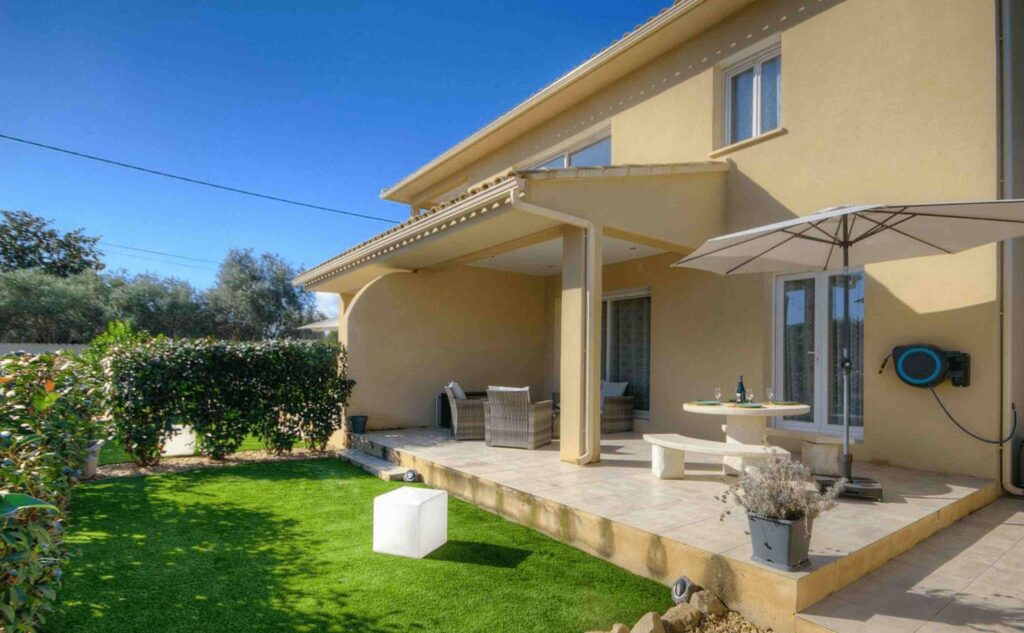 Maison avec terrasse couverte et jardin aménagé, idéale pour des moments en plein air.