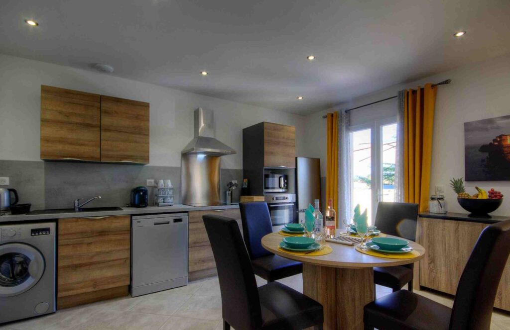 Cuisine moderne avec des armoires en bois clair et une table ronde avec des couverts.